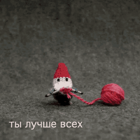 a knitted gnome is holding a ball of yarn and a knitting needles
