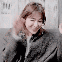 a woman is sitting on a couch and waving her hand .
