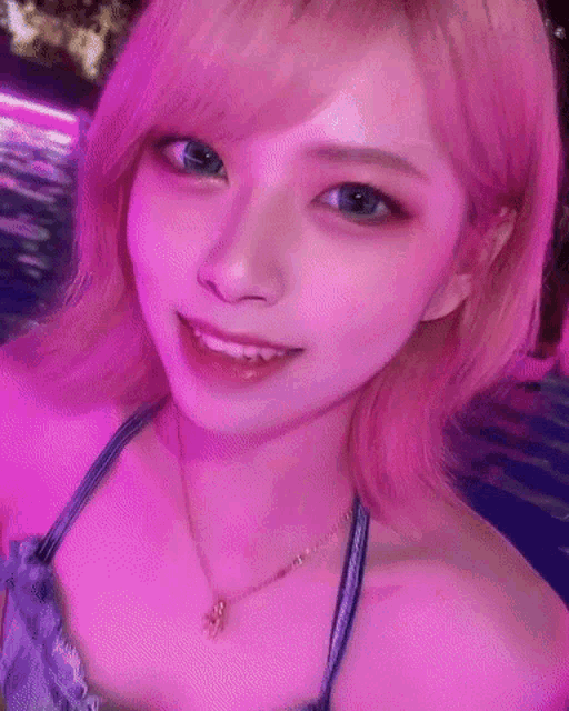 a close up of a woman 's face with pink hair and blue eyes .