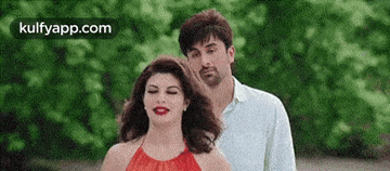 a man and a woman are standing next to each other . the woman is wearing a red top .