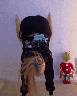 a woman is doing a handstand in front of a grinch toy