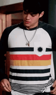 a man wearing a striped shirt and a necklace is taking off his shirt .