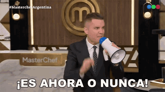 a man in a suit and tie is holding a megaphone in front of a masterchef sign