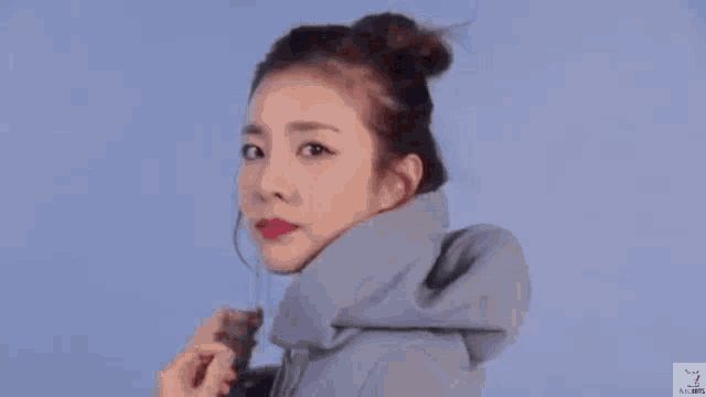 a close up of a woman wearing a grey hoodie and earrings