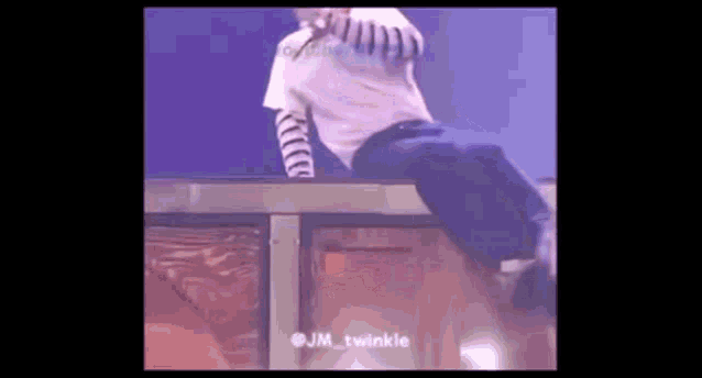 a man in a white shirt and blue pants is standing on a box on a stage .