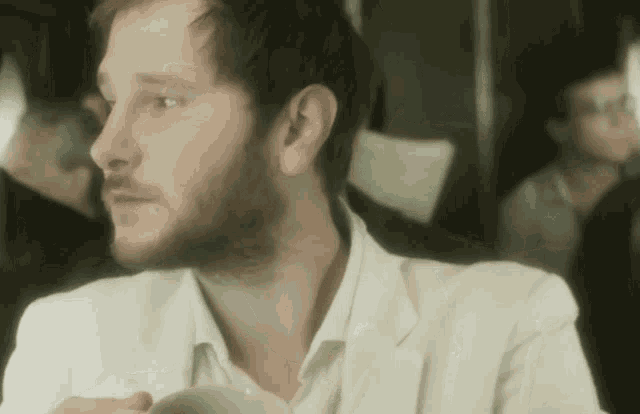 a man with a beard is sitting at a table drinking a cup of coffee