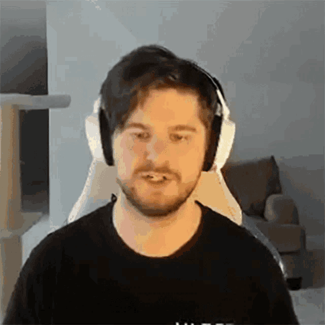 a man with a beard is wearing headphones while sitting in a chair .