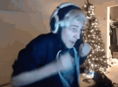 a man wearing headphones is standing in front of a christmas tree in a room .