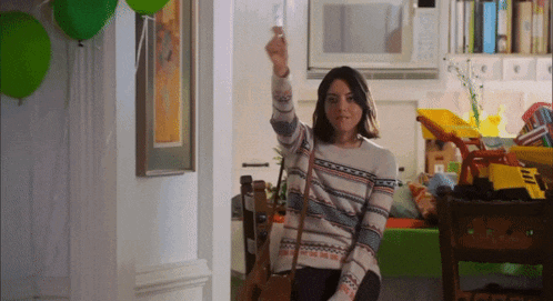 a woman in a striped sweater holds up her fist in the air
