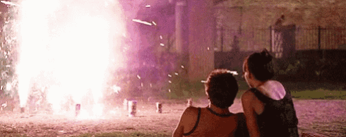 a man and a woman are sitting in front of a firework display .