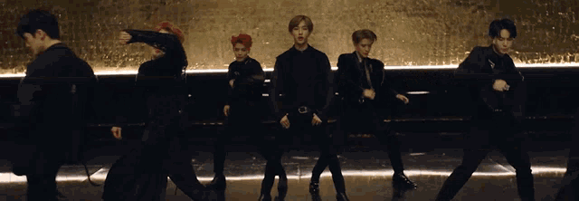 a group of men are dancing in front of a gold background