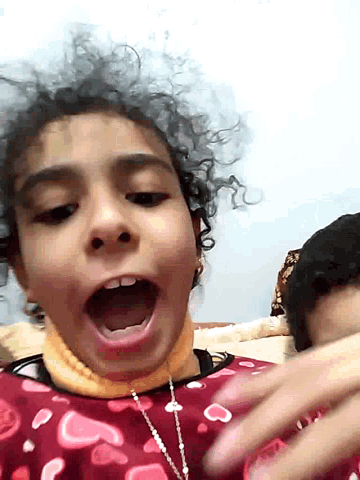 a young girl with curly hair is making a funny face with her mouth open