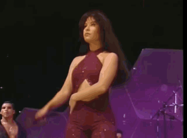 a woman in a red jumpsuit is singing into a microphone