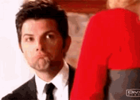 a man in a suit and tie is standing next to a woman in a red diva shirt