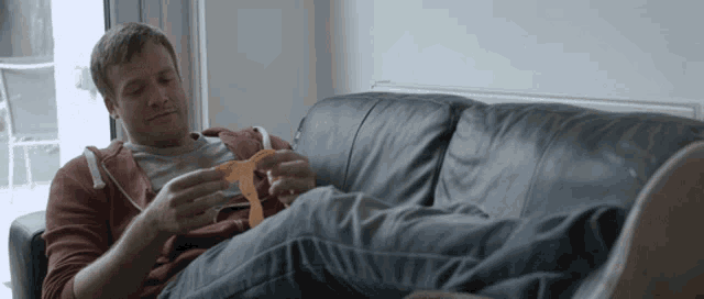a man is sitting on a couch eating a tortilla chips