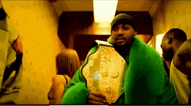 a man in a green coat is holding a gold belt