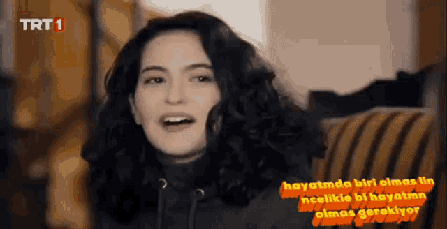 a woman sitting on a couch with trt 1 written on the bottom right