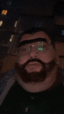 a man with glasses and a beard is wearing a black shirt
