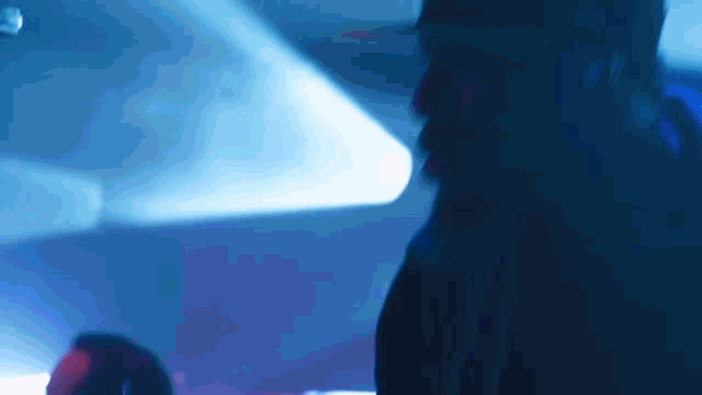 a blurry picture of a person in a dark room with a blue light behind them