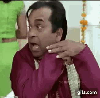 a man is making a funny face while sitting at a table with a woman .