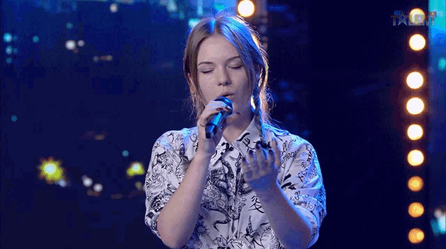 a girl singing into a microphone with the word talent on the bottom left