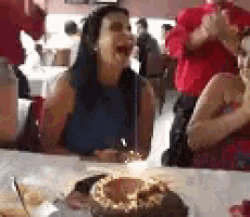 a woman is sitting at a table with a cake and a candle in it .