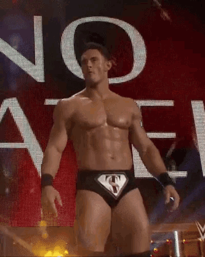a shirtless wrestler is standing in front of a large screen that says no angel