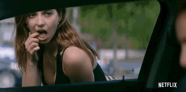 a woman is licking her lips while sitting in a car with netflix written on the bottom right