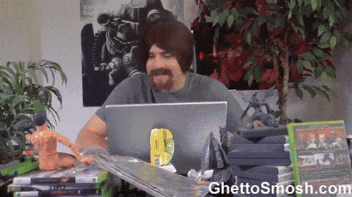 a man sitting in front of a laptop with the website ghettosmosh.com written on the bottom