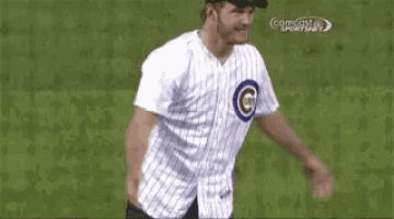 a man in a cubs jersey is dancing on a baseball field