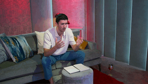 a man is sitting on a couch with a book on a table