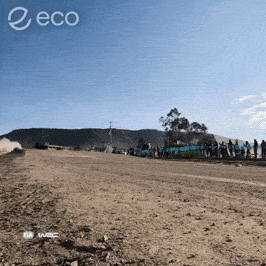 a group of people standing on the side of a dirt road with the word eco on the bottom right