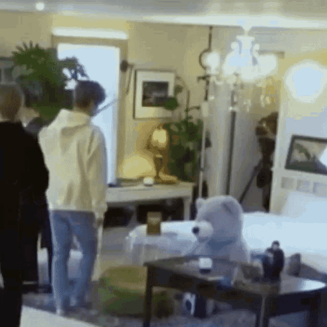 a group of people standing in a living room with a teddy bear on a table