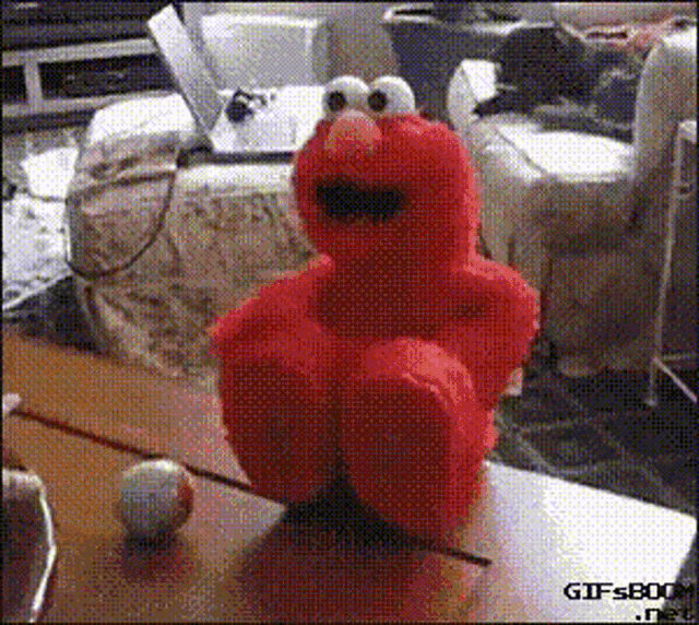 elmo from sesame street is sitting on a table next to a ball