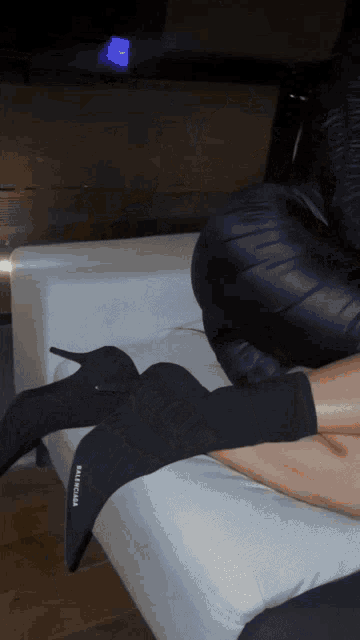 a woman wearing a pair of balenciaga boots is laying on a bed
