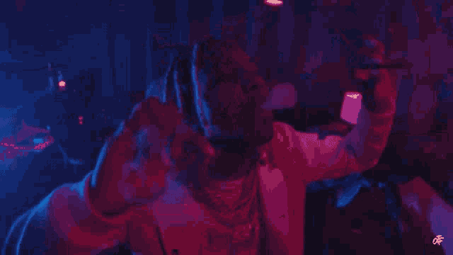a group of people are dancing in a dark room with blue and red lights .