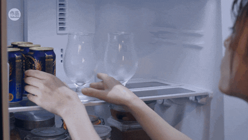 a person taking a glass from a fridge that has chinese writing on the door