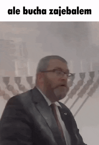 a man in a suit and tie is standing in front of a menorah in a synagogue .