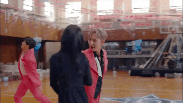 a man in a pink suit is talking to a woman on a basketball court .