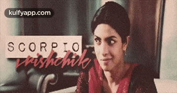 a woman is sitting at a table with a sign that says scorpio on it .