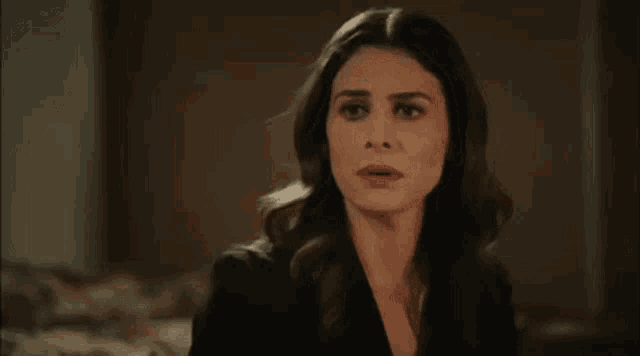 a woman in a black jacket is making a funny face and looking at the camera .