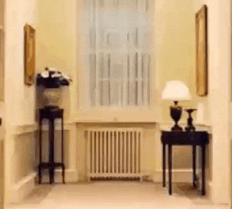 a hallway with a table , lamp , and a window .