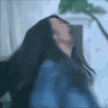 a blurry picture of a woman 's face with her hair blowing in the wind