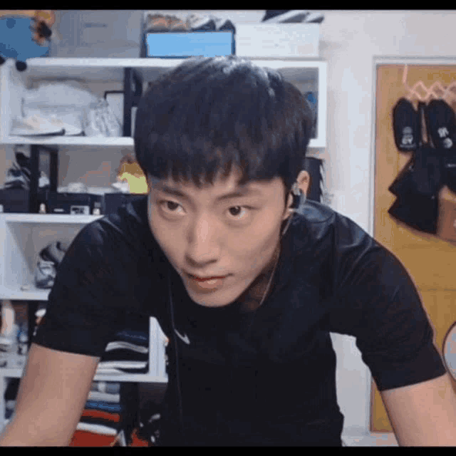 a young man wearing headphones and a black shirt is sitting in a room .