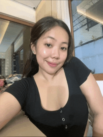 a woman in a black shirt is taking a selfie in front of a large window