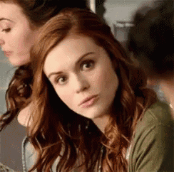 a woman with red hair is looking at the camera while sitting next to another woman .