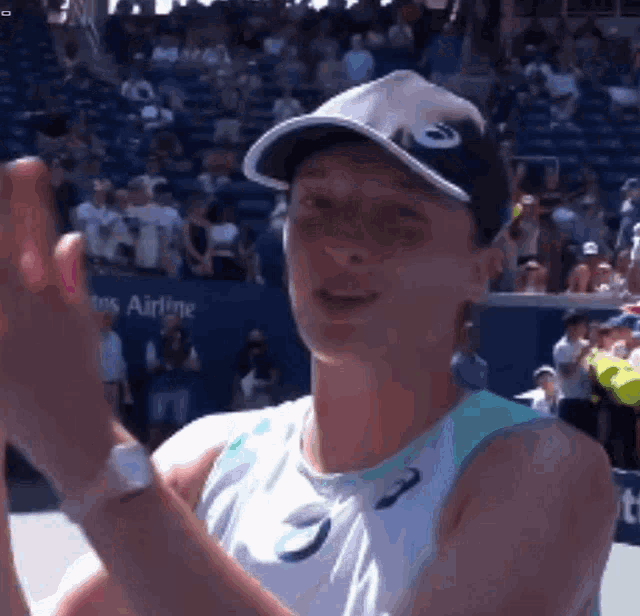 a woman wearing an asics hat is giving a high five to the crowd