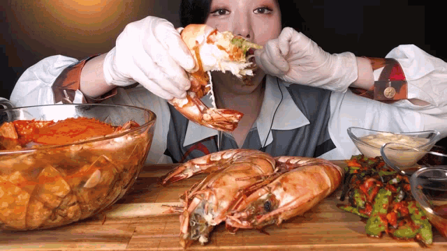 a woman in white gloves is eating a large shrimp with a knife