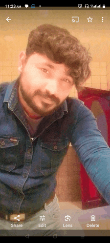 a phone screen shows a man taking a selfie at 11:23