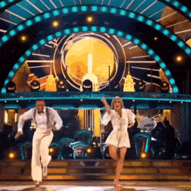 a man and a woman are dancing on a stage in front of a clock .